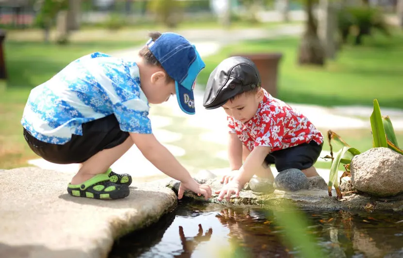 Two boys playing near a pond