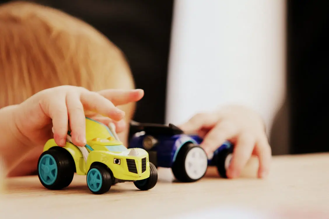 Child rolling two toy cars